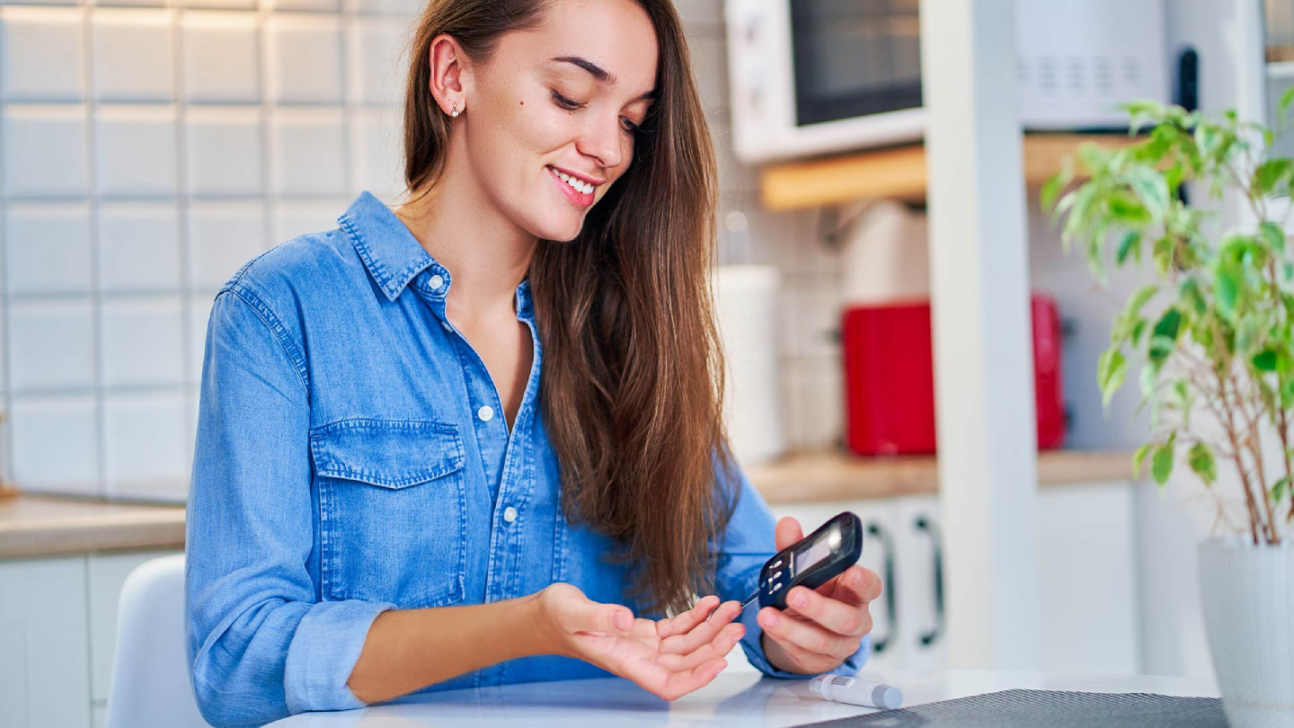 Усмихната жена измерва кръвната захар с глюкомер