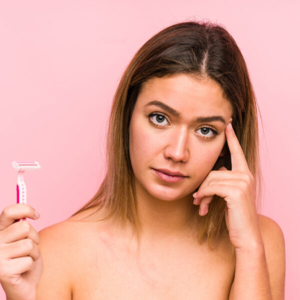 Млада жена, държаща бръснач и изглеждаща притеснена