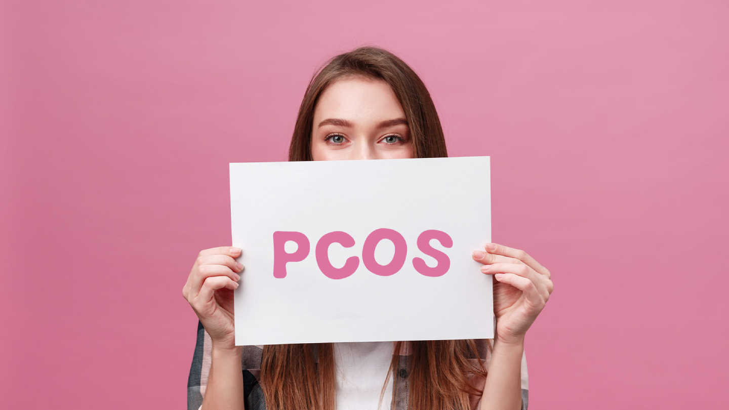 Жена, държаща табелата PCOS на розов фон